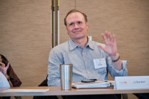Photo of JJ Bartlett smiling and raising his hand