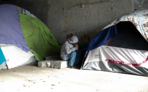 Photo of a man sitting in between tents outside in Boston
